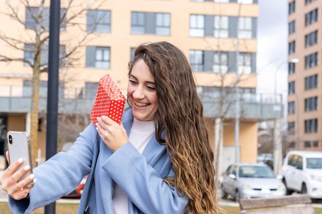 Femme montrant un cadeau pour son petit ami tout en lui parlant par appel vidéo. célébration d'une journée spéciale. Saint Valentin, anniversaire, anniversaire, Noël...