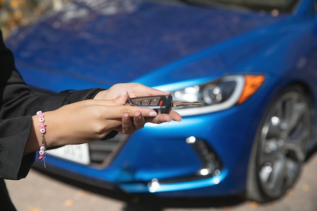 Femme montrant la clé de la voiture sur le fond d'une voiture