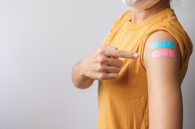 Femme montrant du plâtre après avoir reçu le vaccin covid 19. Vaccination, immunité collective, effet secondaire, dose de rappel, passeport vaccinal et pandémie de coronavirus