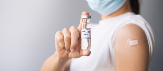 femme montrant un flacon de vaccin covid-19