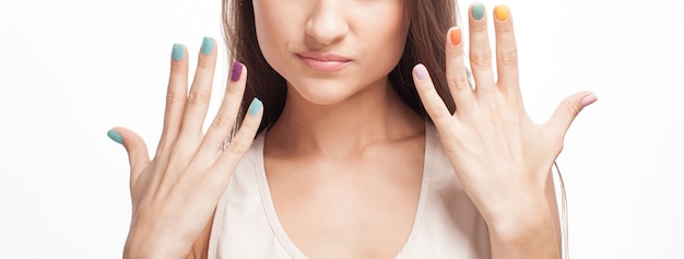 Femme montrant ses ongles colorés sur blanc