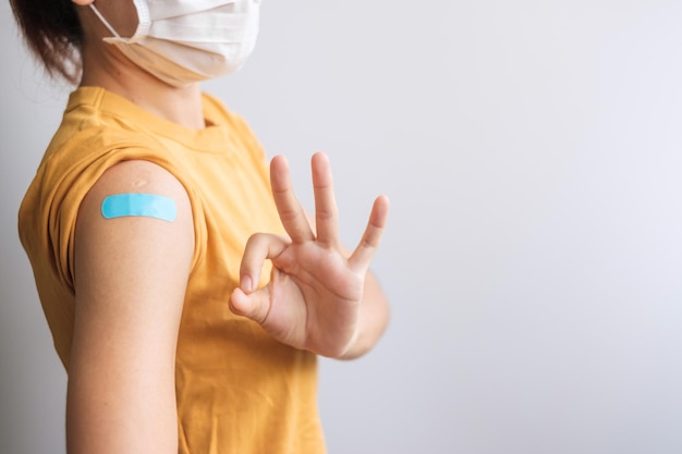 Femme montrant un signe OK avec un bandage après avoir reçu le vaccin covid 19. Vaccination, immunité collective, effet secondaire, dose de rappel, passeport vaccinal et pandémie de coronavirus