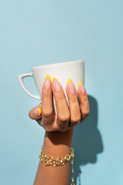 Photo femme montrant son nail art sur les ongles avec une tasse