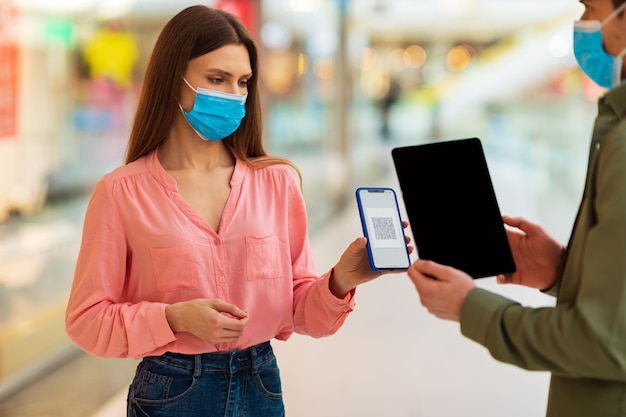 Femme montrant un téléphone avec code qr pour scanner dans un supermarché