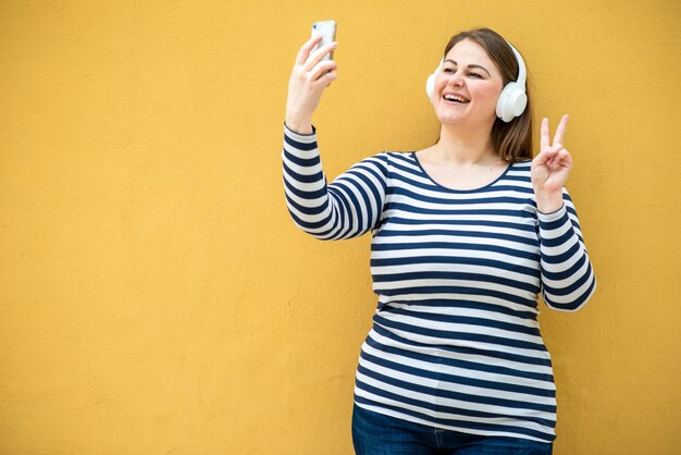 femme montre un geste de paix et prend un selfie sur un smartphone