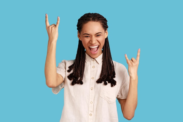 Une femme montre un geste de rock and roll signe de métal lourd aime la musique préférée sur la fête a le visage de fouines