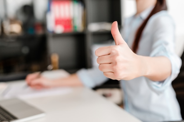 Femme montre pouces au bureau sur un lieu de travail