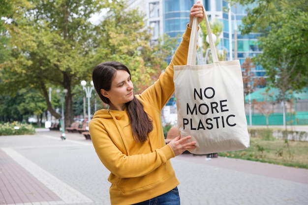 Photo une femme montre un sac réutilisable en tissu avec le texte plus de plastique