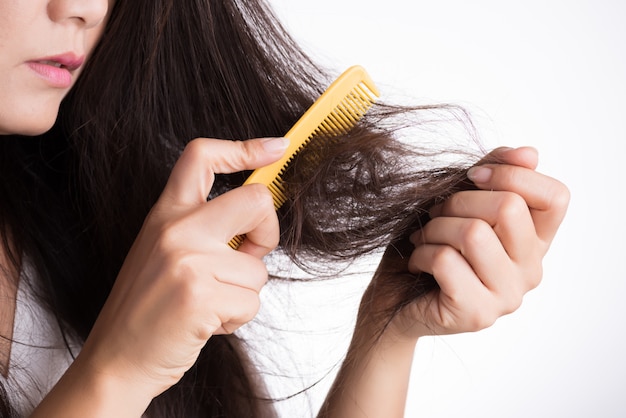 Femme montre son pinceau avec les cheveux endommagés de longue perte