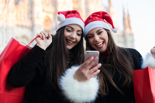 Une femme montre sur un téléphone portable quelque chose à son amie lors de ses achats à Milan