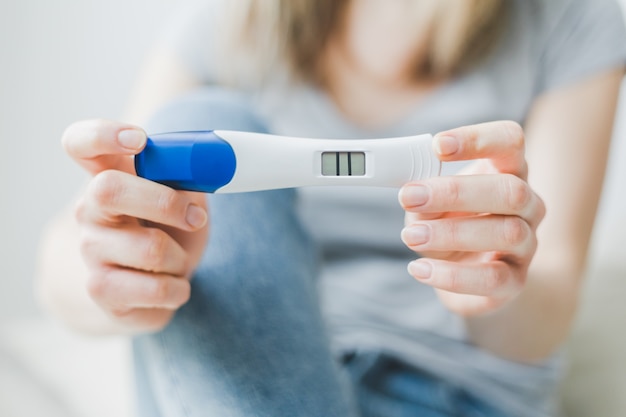 La femme montre un test de grossesse positif