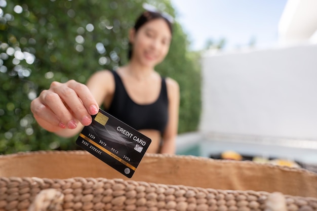 Femme montrer une carte de crédit avec petit-déjeuner flottant dans la piscine lors d'un voyage de luxe dans une villa de luxe