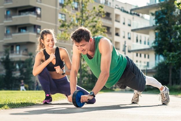 Femme motivant l'homme exerçant avec roue tonique