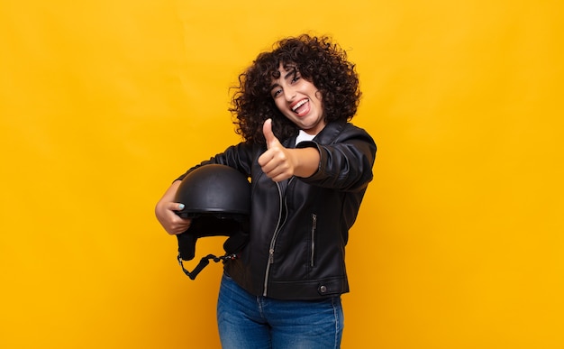 Femme de motocycliste se sentir fier, insouciant, confiant et heureux, souriant positivement avec les pouces vers le haut