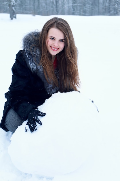 Une femme moule une grosse boule hors de la neige