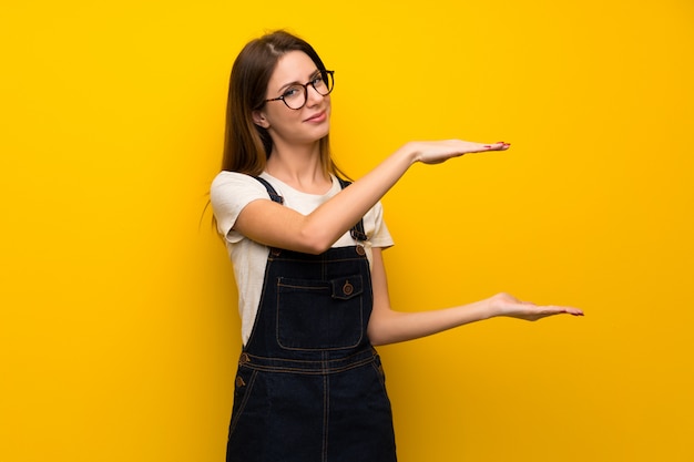 Femme sur un mur jaune tenant un fond pour insérer une annonce