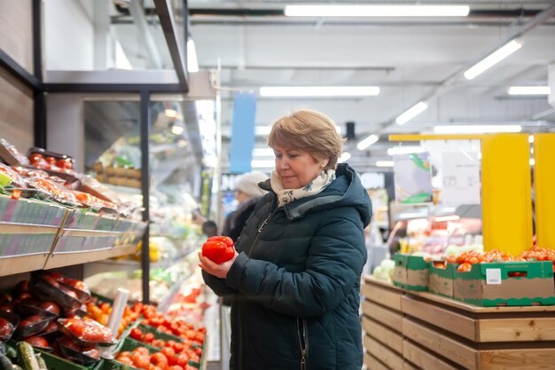 Femme mûre achetant des légumes au marché d'agriculteurs