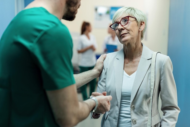 Femme mûre consolé par le chirurgien tout en lui parlant dans un couloir de l'hôpital