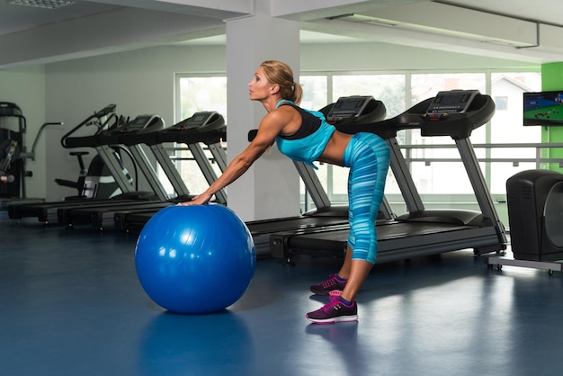 Femme mûre exerçant sur le ballon dans la salle de gym et muscles de la flexion Muscular Athletic Bodybuilder Fitness Model