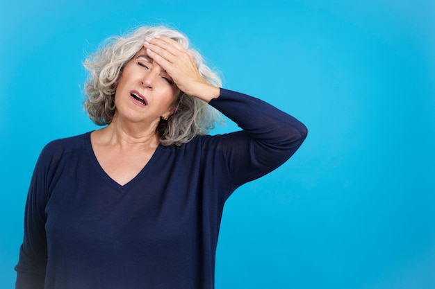 Femme mûre avec la main sur le front exprimant des maux de tête