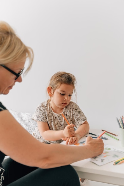 Femme mûre mamie avec petite-fille d'âge préscolaire dessinant ensemble à la maison