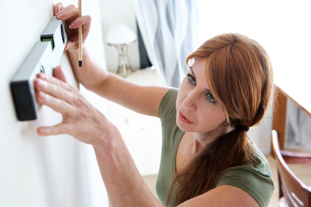 Femme mûre marquant sur le mur avec le niveau