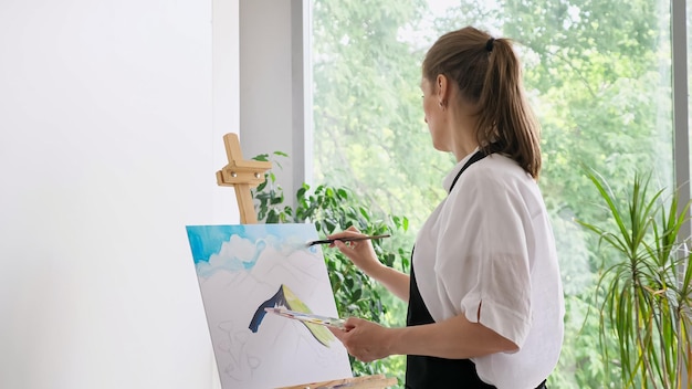 Femme mûre peint le ciel sur toile avec gros plan de pinceau