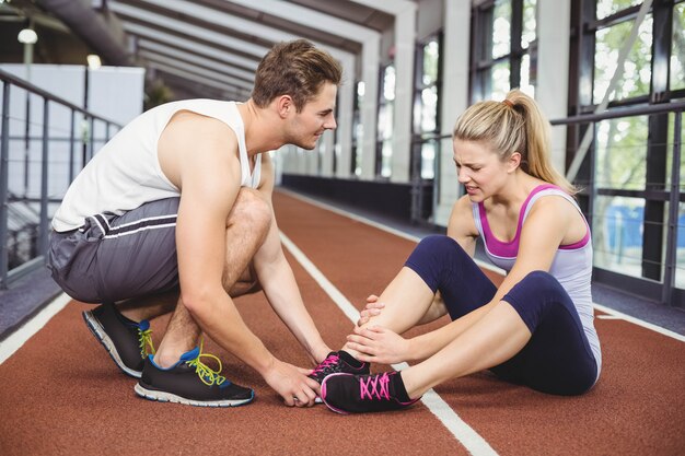 Femme musclée ayant une blessure à la cheville dans un gymnase de crossfit