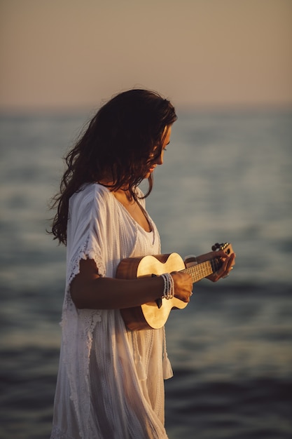 Femme musicienne avec ukulélé sur les vacances d'été à la plage