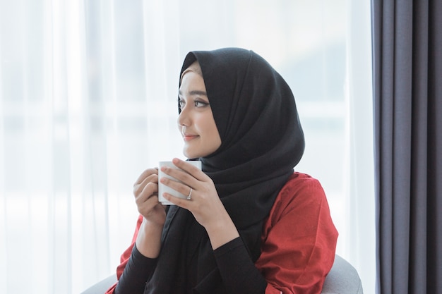 Femme musulmane appréciant le café à la maison