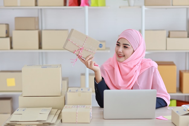 Femme musulmane asiatique active en costume bleu assis et travaillant avec ordinateur