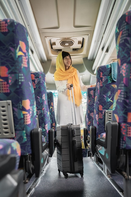 Photo femme musulmane asiatique faisant le voyage de retour dans sa ville natale en prenant un bus