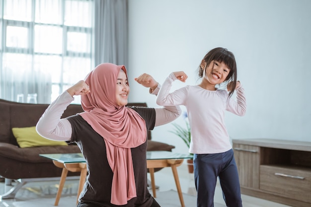 Femme musulmane asiatique et fille faisant de l'exercice et du sport à la maison pendant l'auto-isolement