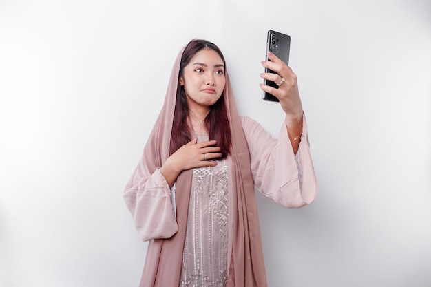 Une femme musulmane asiatique malheureuse portant un foulard essuie ses larmes de désespoir pendant un appel vidéo