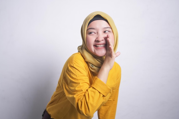 Une femme musulmane asiatique portant le hijab et une chemise jaune crie et crie