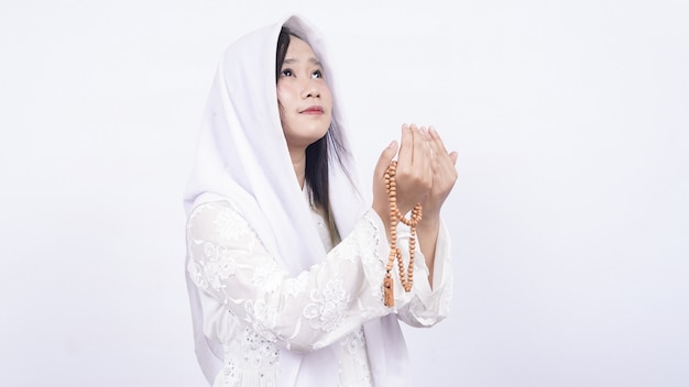 Femme musulmane asiatique portant des perles de prière prient en blanc