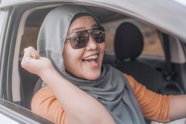 Une femme musulmane asiatique souriante en conduisant s'amusant dans un voyage de vacances en voiture.