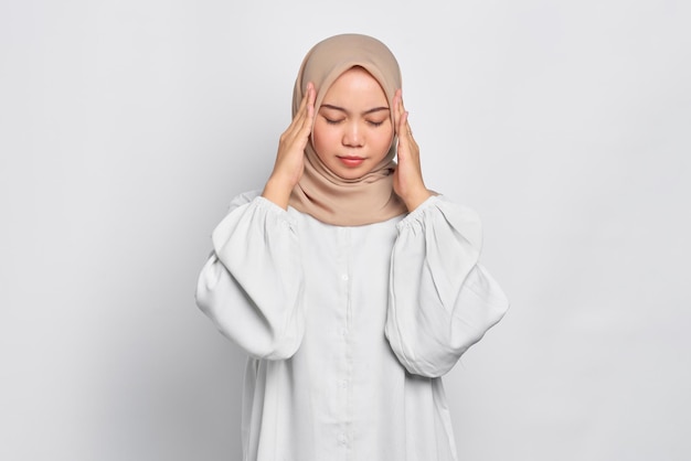 Femme musulmane asiatique stressée touchant ses tempes et ayant des maux de tête isolés sur fond blanc