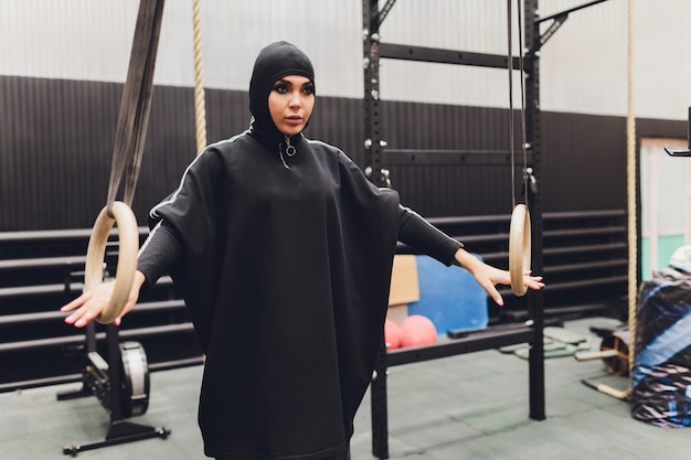 Femme musulmane en hijab exerçant dans une salle de sport.