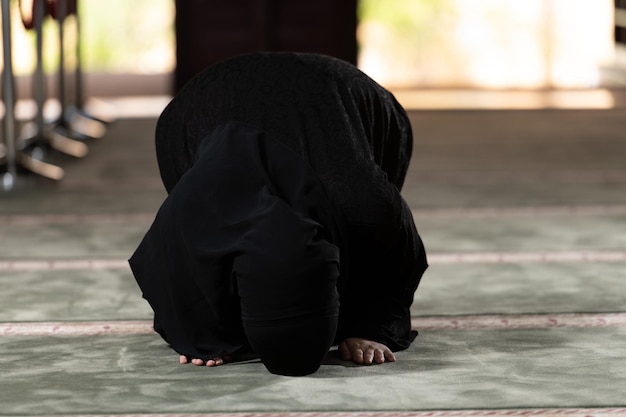 Femme musulmane en hijab priant sur un tapis