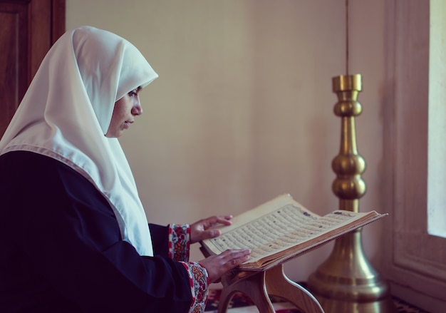 Femme musulmane lisant le Coran et priant dans la mosquée