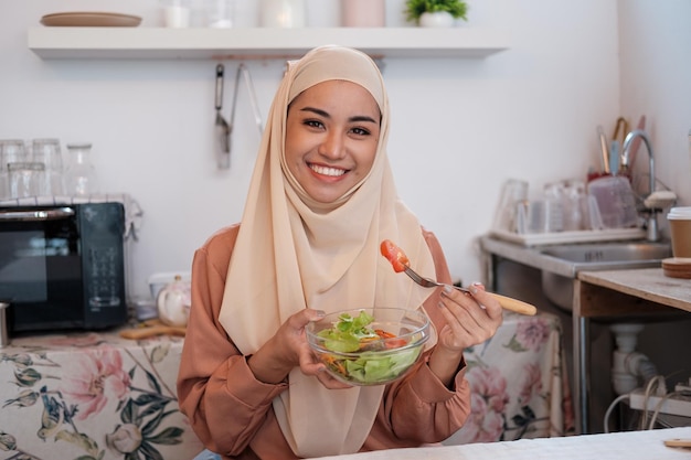 Femme musulmane mature en hijab mélangeant prépare une salade de légumes dans la cuisine concept de nourriture végétalienne végétarienne