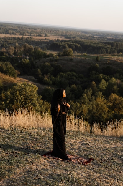 Femme musulmane noire priant sur le tapis. Solat priant sur la belle colline. Salah prière traditionnelle.