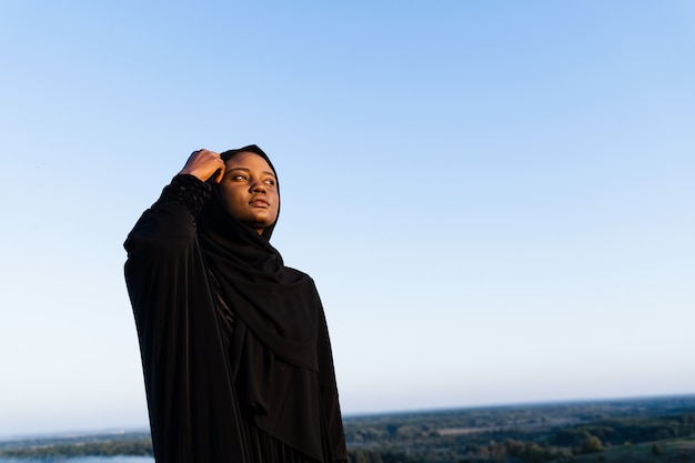 Femme musulmane noire vêtue d'une robe noire sur fond bleu. religion islamique. Célébrer le ramadan.