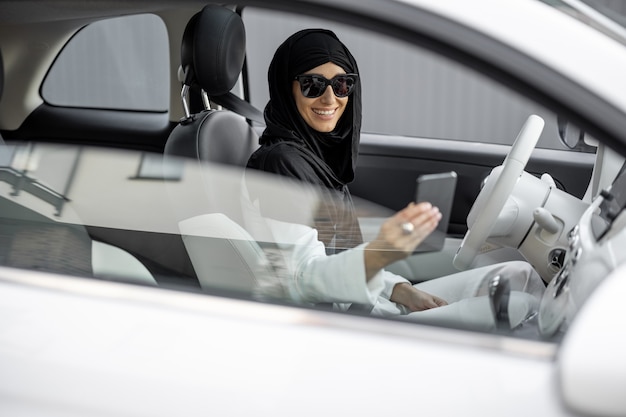 Une femme musulmane parle au téléphone en conduisant une voiture