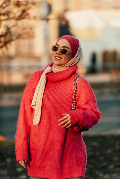 Photo une femme musulmane portant un hijab marche dans les rues de la ville dans une tenue moderne combinée avec des lunettes de soleil mise au point sélective