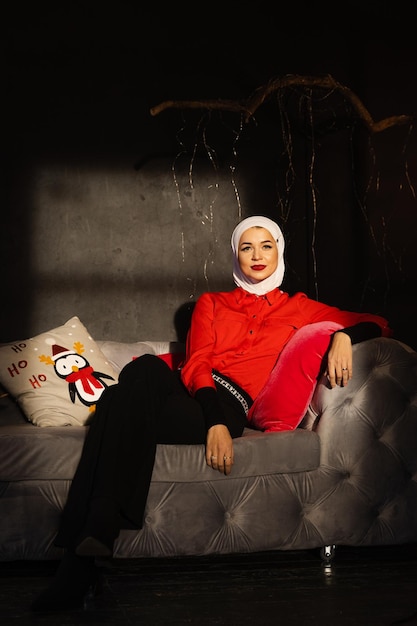Femme musulmane près des lumières de Noël et décoration en studio. Modèle musulman professionnel posant à la veille du nouvel an