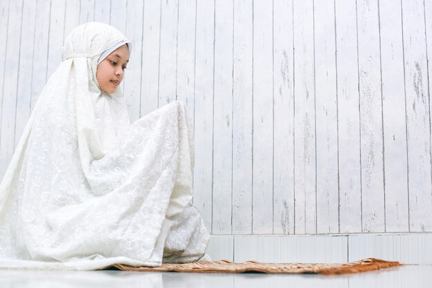 Femme musulmane priant Dieu avec mendicité geste de la main sur le tapis de prière