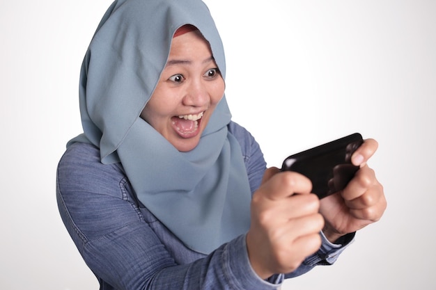 Une femme musulmane ravie de jouer à des jeux sur téléphone
