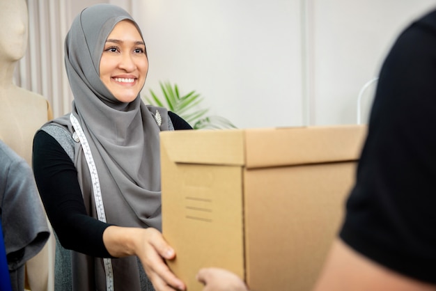 Femme musulmane recevant une boîte à colis chez un livreur